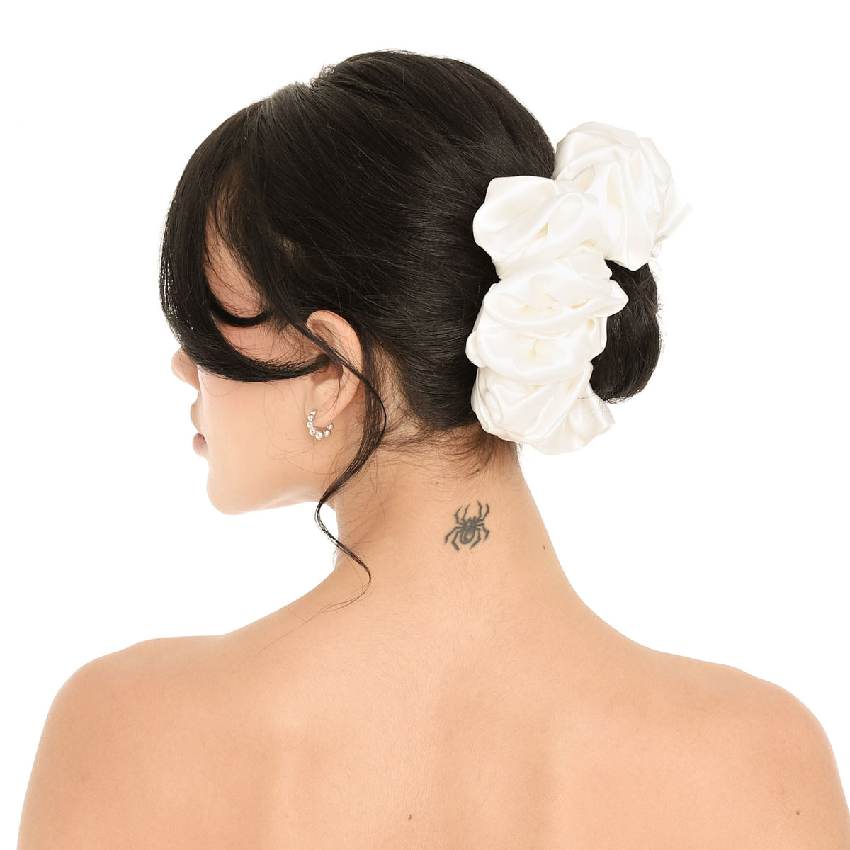 Close-up of the white silk Faeli Scrunchie wrapped around a low bun, showing the glossy silk and the full, gathered ruffles **white
