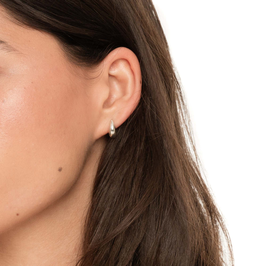 Model wearing Fala puffed sterling silver huggie hoop earring hugging the ear