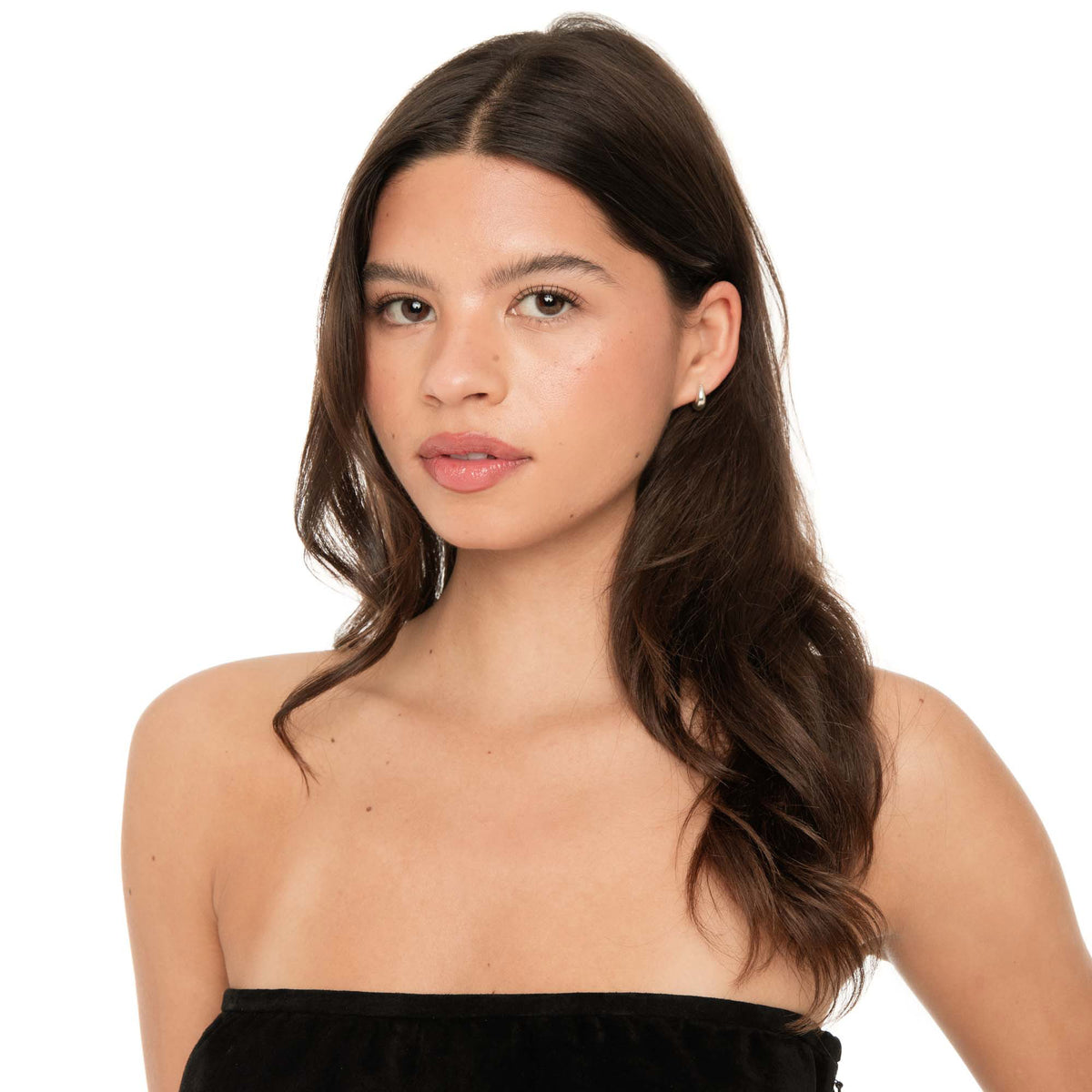 Model wearing sterling silver Fala huggie hoop earrings with strapless black top