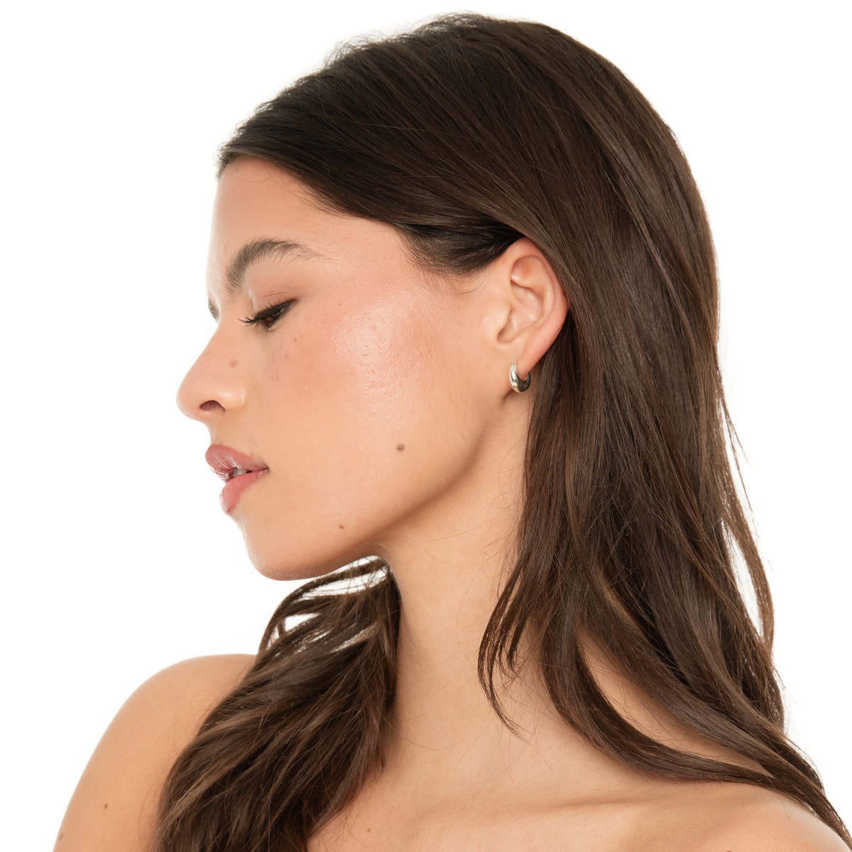 Side profile of model wearing Fala sterling silver huggie hoop earrings