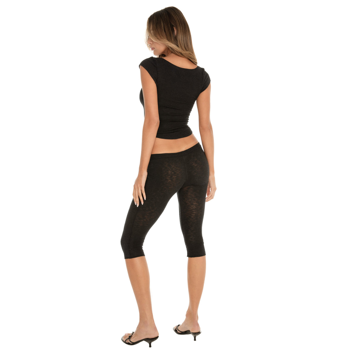 Back view of a fitted cap sleeve henley top and capri leggings, featuring a clean, contoured back and the smooth, body-skimming silhouette **black