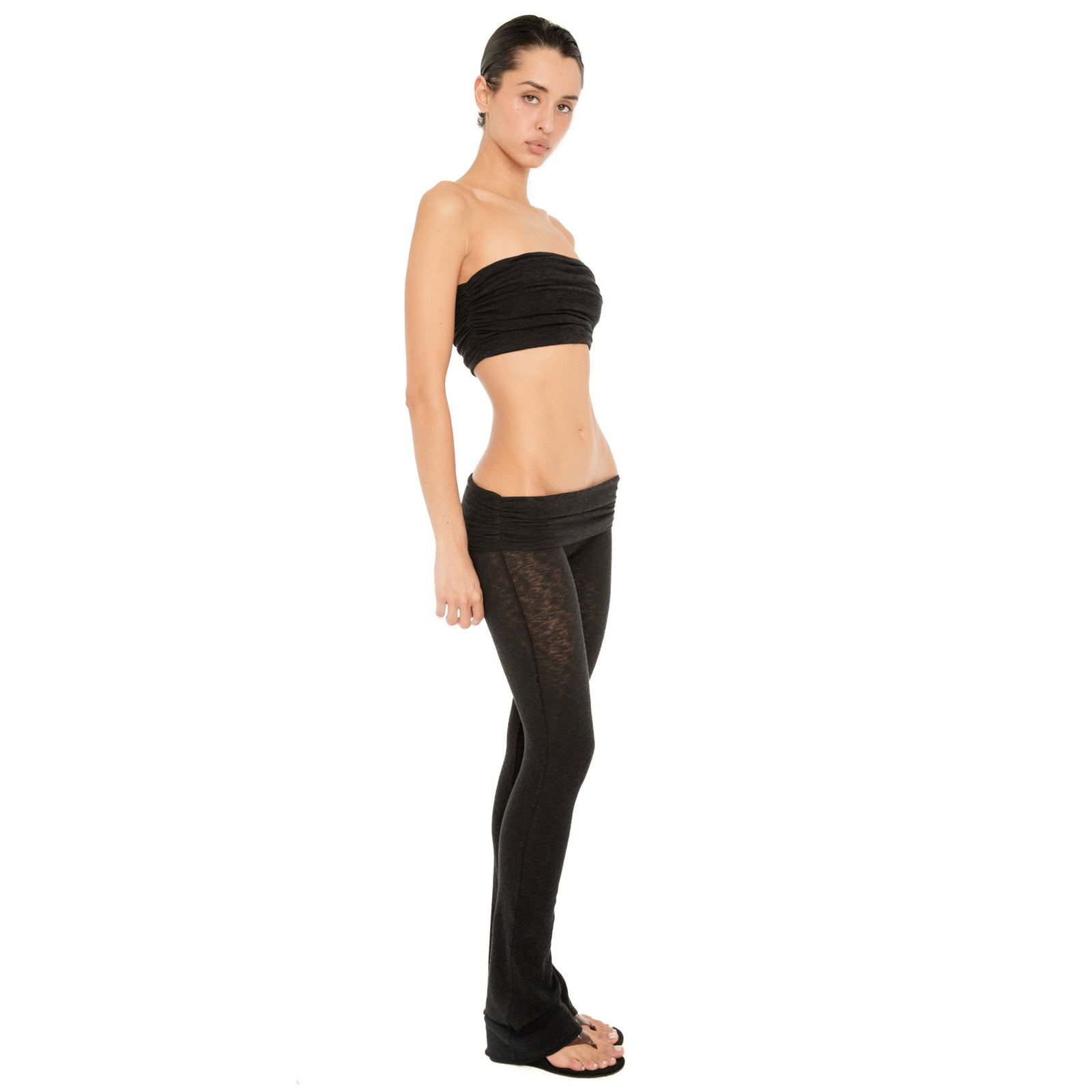 Side view of the Meili Pant in Black, highlighting the low slung waistband, fitted leg and subtle flare at the hem. **black