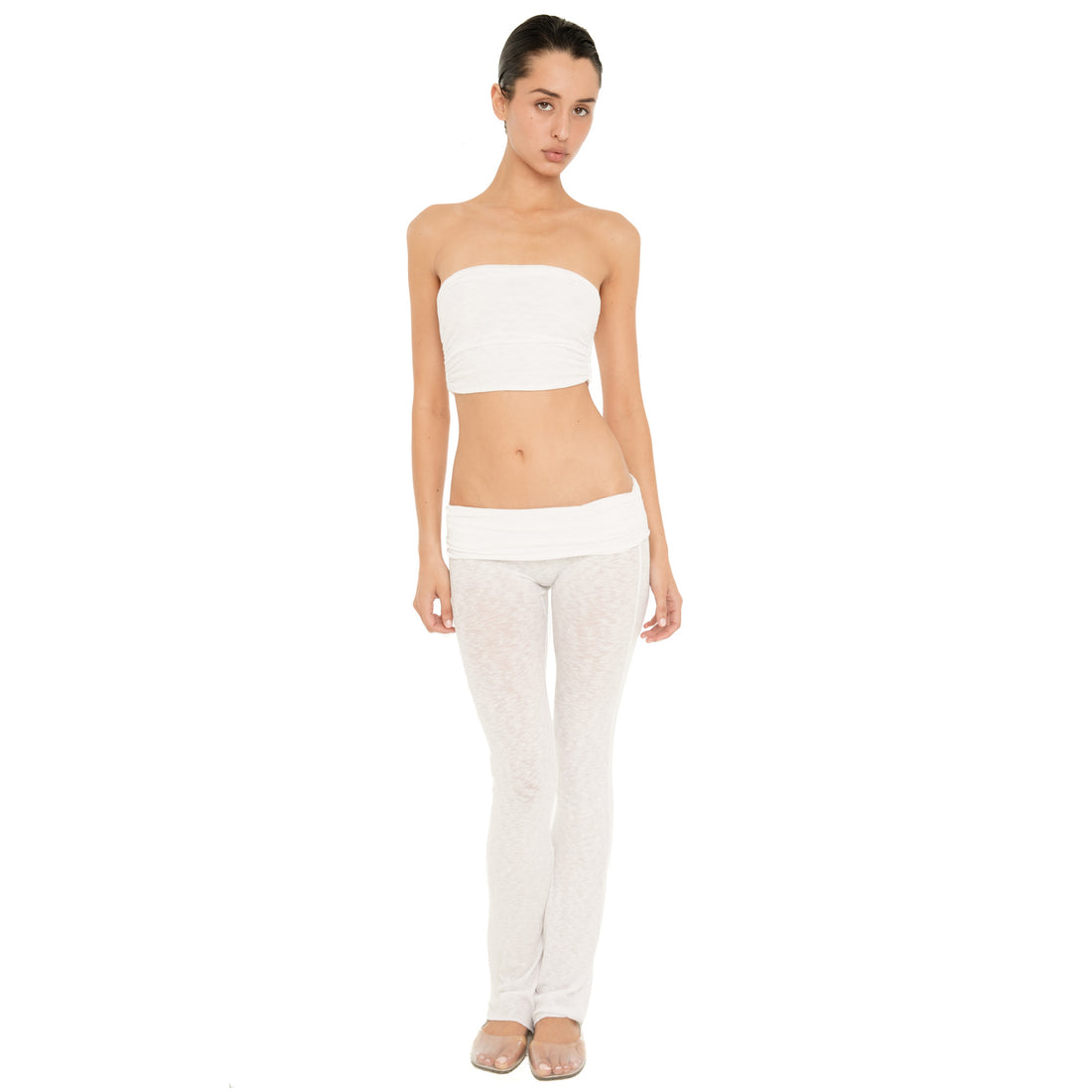 Full-length front view of model wearing the Meili Pant in White, a sheer low rise fitted pant with a wide folded waistband and subtly flared leg. **white