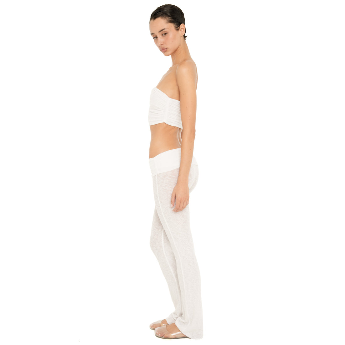 Side view of the Meili Pant in White, highlighting the low rise waistband, fitted silhouette and full-length subtly flared leg. **white
