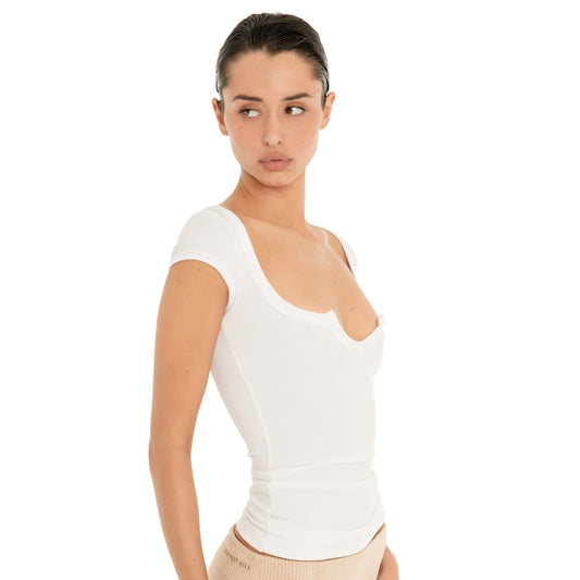 Three-quarter close-up of the white Impy Tee, highlighting the low scoop neckline with pointed center notch and curved detailing at the bust. **white