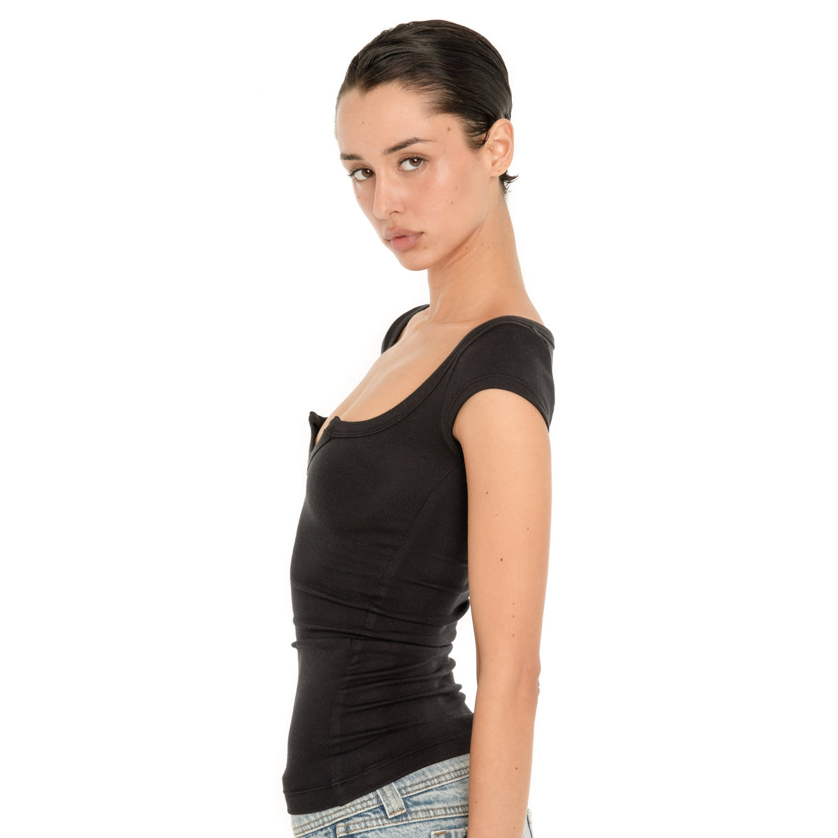 Three-quarter side close-up of model wearing the black Impy Tee, highlighting the fitted ribbed fabric and neckline construction **black