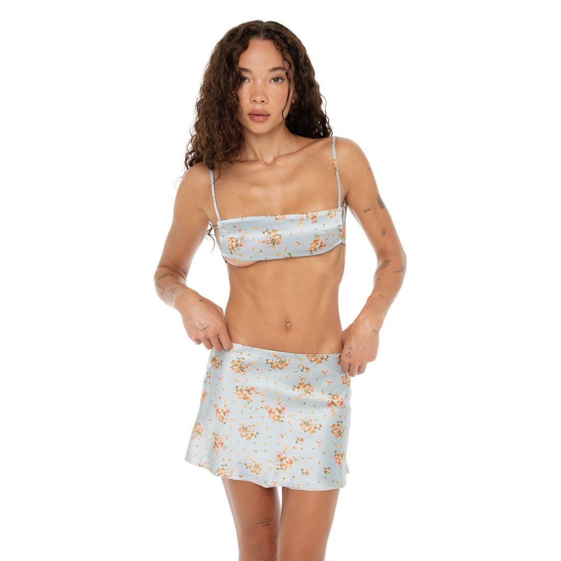 Model adjusting waistline of Itsi Floral Skirt in Sky floral silk. **sky