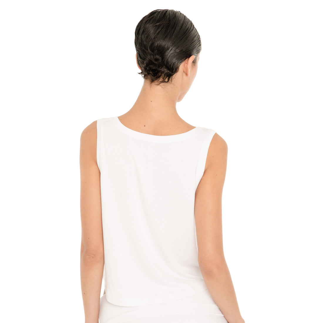 Back view of model wearing the white Kasia Top, showing the high rounded back neckline, wide straps and relaxed cropped silhouette. **white