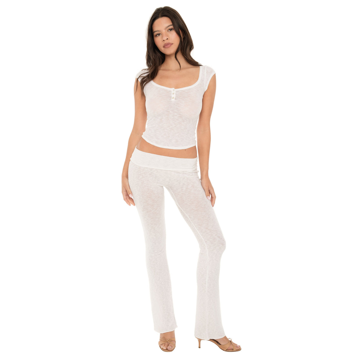 Model wearing a black short sleeve scoop neck top with a three-button henley placket at center front, styled with matching black fitted pants. **white