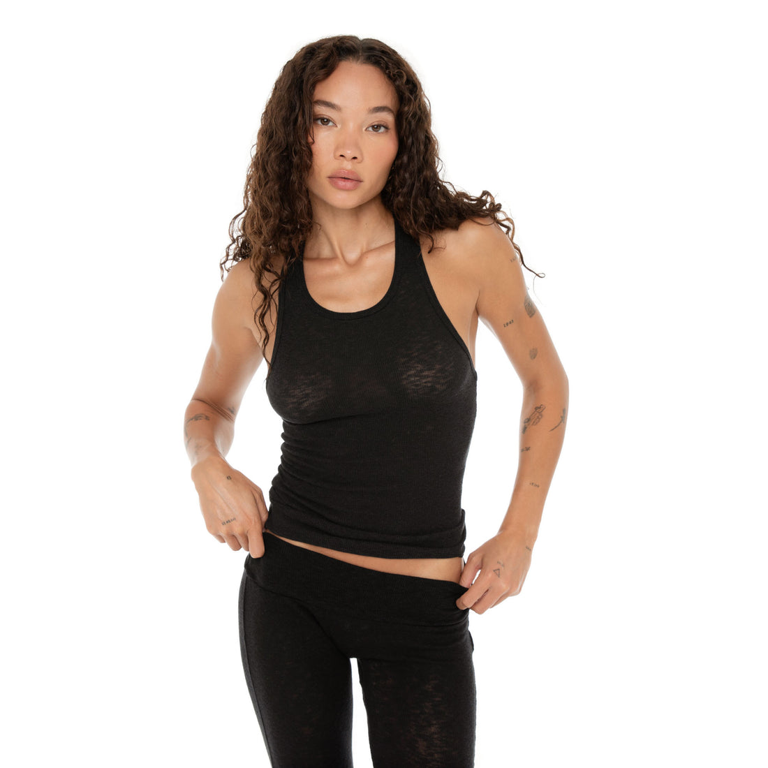 Woman adjusting her waistband while wearing black Kimi Tank, front view. **black