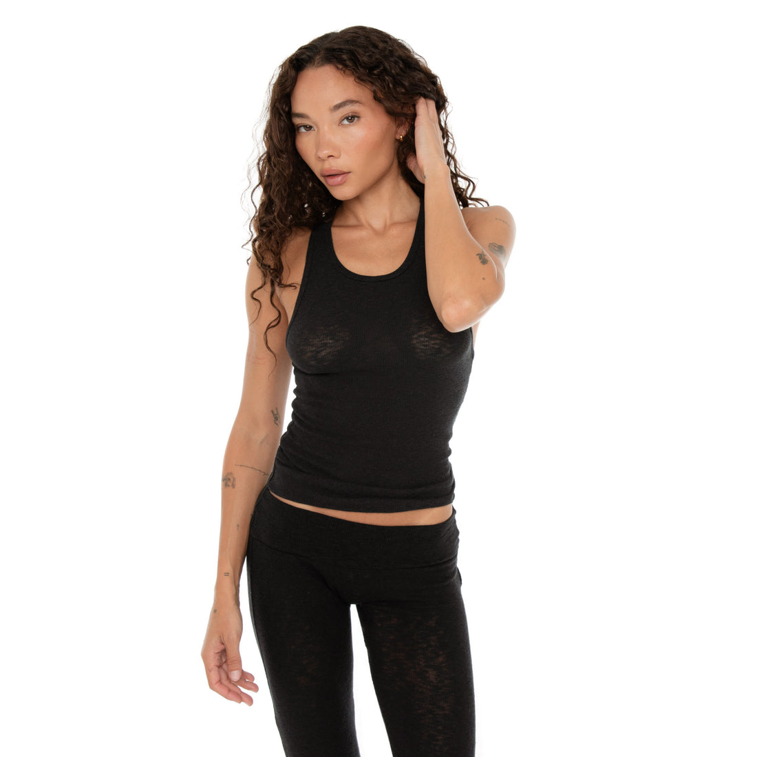 Woman posing with hand to her head in black racerback tank, front-facing view. **black