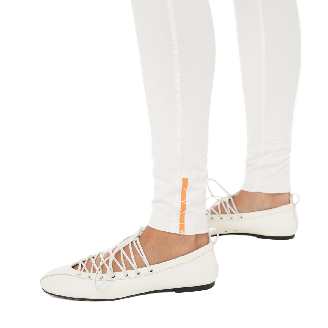 Close-up of Kixa Legging ankle with orange Are You Am I logo detail. **white