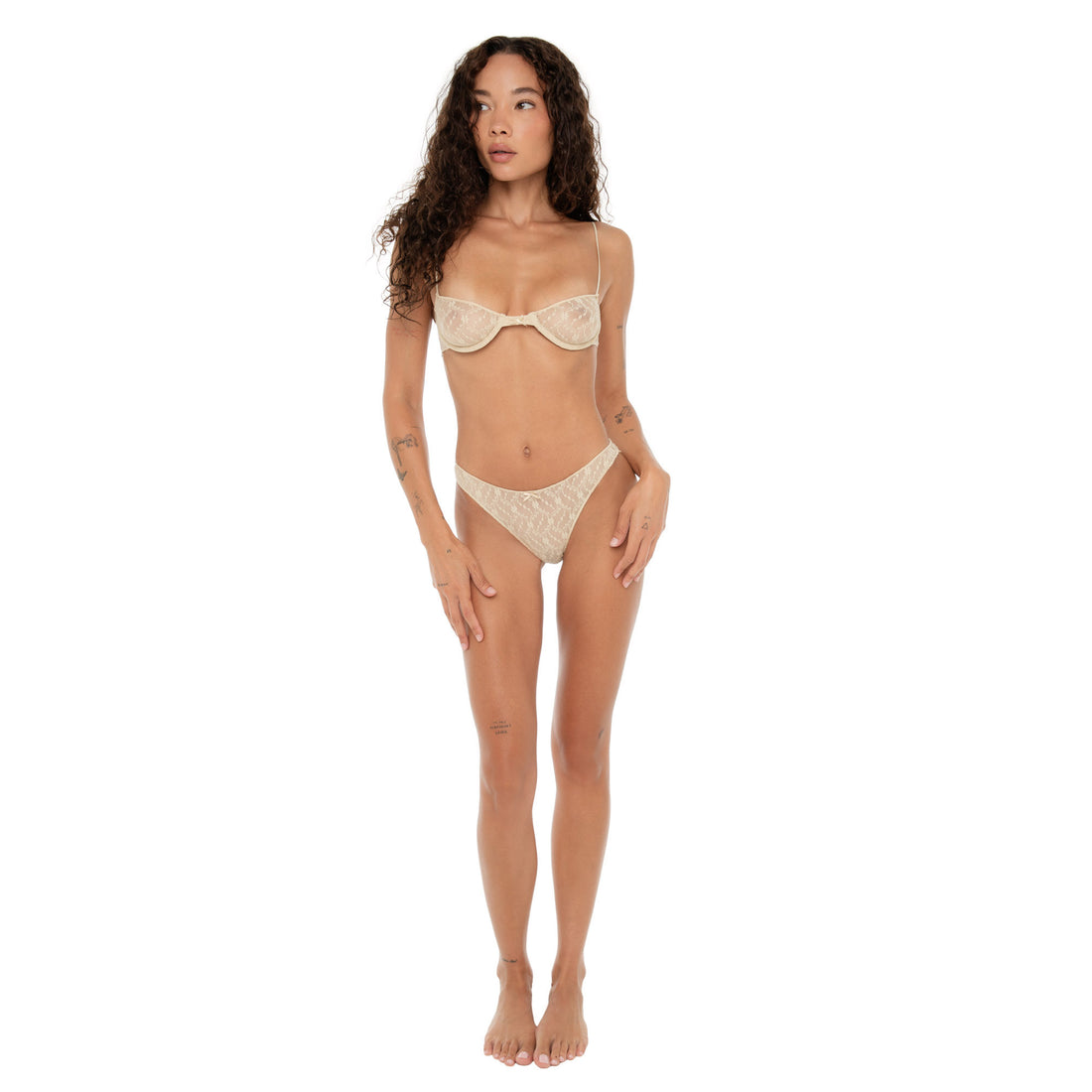 Model standing front-facing wearing sheer nude lace bra and matching high-cut bottoms against a white background. **nude