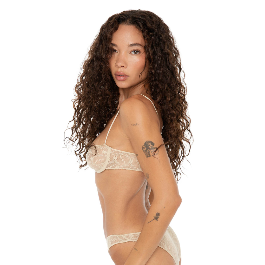Side profile view of model wearing nude lace bra and panties, highlighting delicate lace detail and adjustable strap. **nude