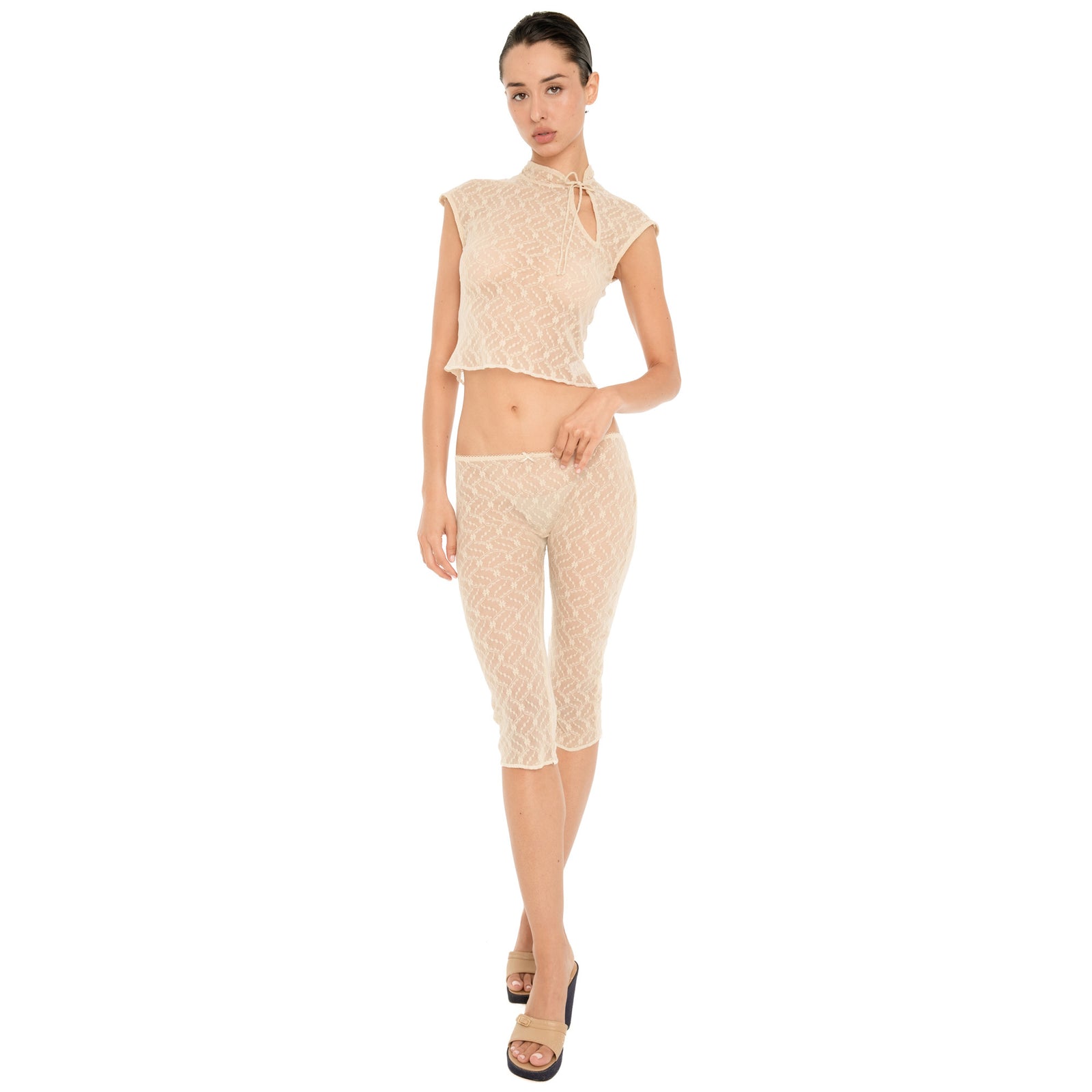 Model wearing the Lyli Capri in nude sheer floral lace with a matching cropped lace top, shown full length against a white background. **nude