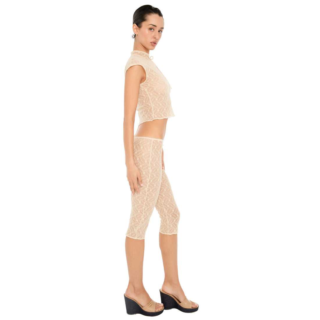 Model shown in profile wearing the nude sheer floral lace Lyli Capri with a matching cropped lace top, highlighting the capri length and fitted silhouette. **nude