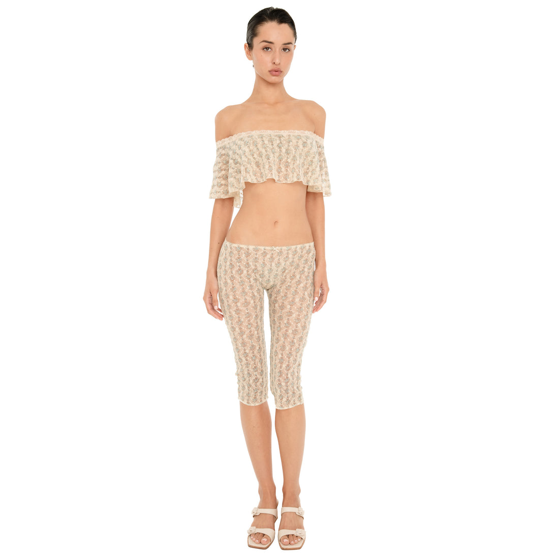 Model facing forward in a cream sheer floral lace off shoulder top and matching low rise, knee length Lyli Capri pants, styled with cream heeled sandals. **sky blossom