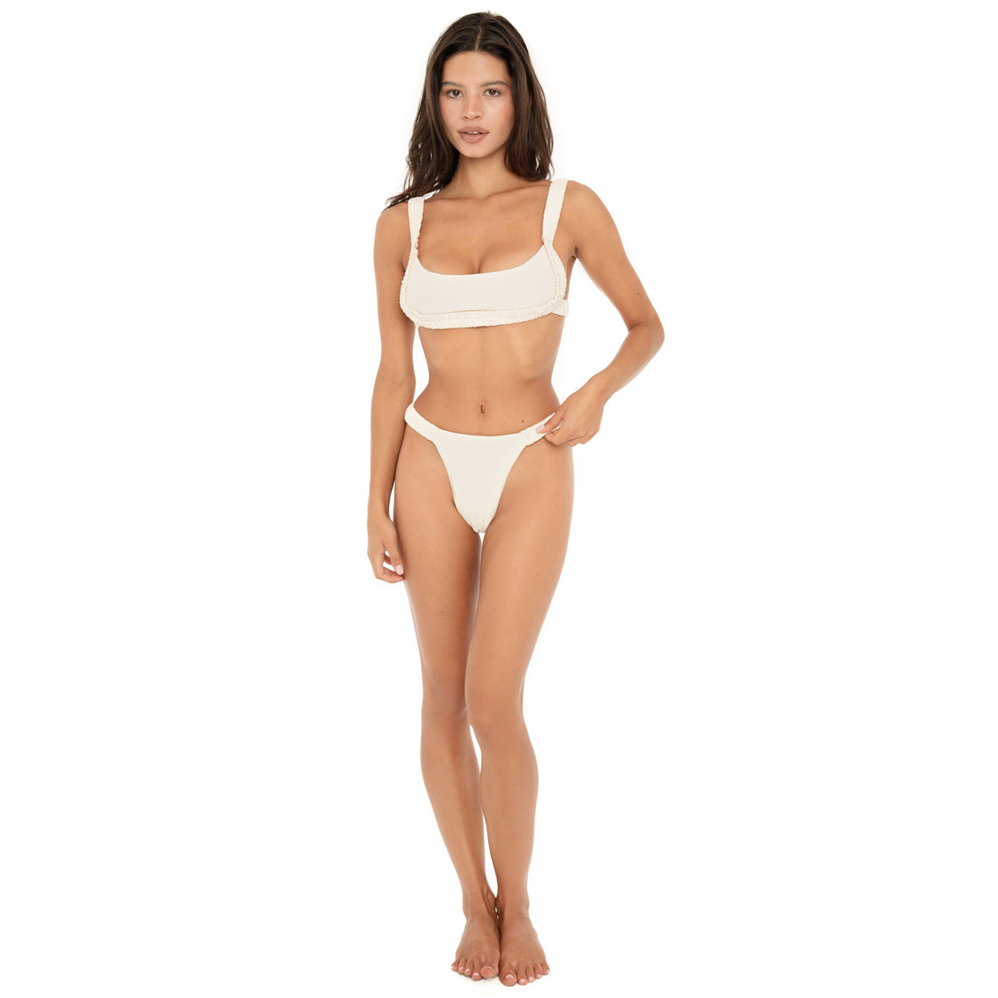 Model wearing the ARE YOU AM I Nailah Swim Top in Cream with matching bikini bottoms, featuring a scoop neckline and gathered trim **cream