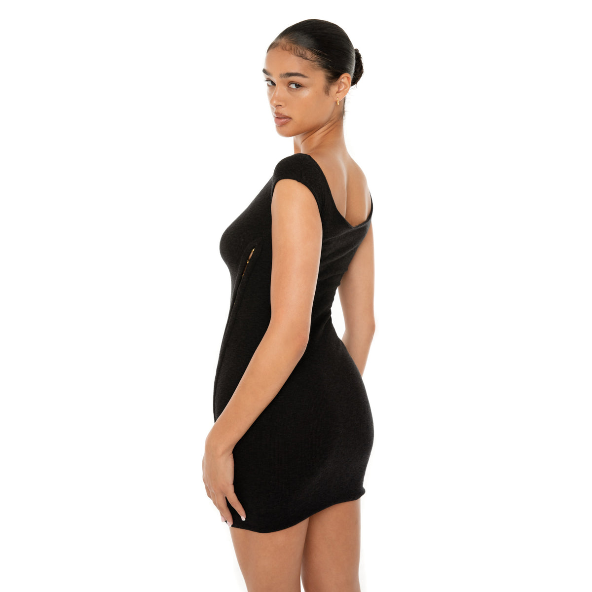 Model wearing the black Nikisa Dress — off-shoulder ribbed mini with gold hook-and-eye closures running down each side, hugging the body in a sculpted silhouette.**black