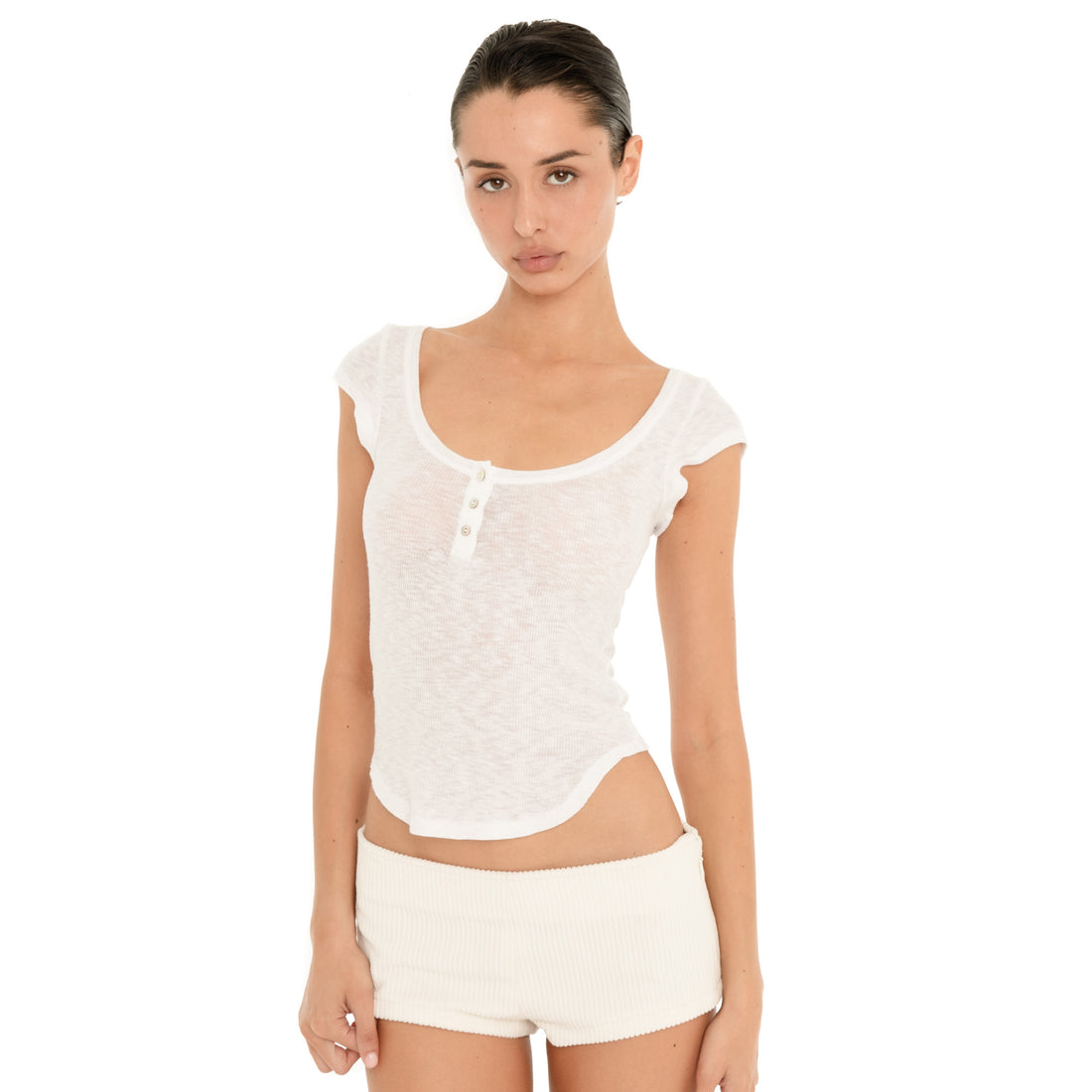 Front view of model wearing the ivory Nimue Short, showing the low-rise waist, fitted micro silhouette and ribbed fabric. **ivory