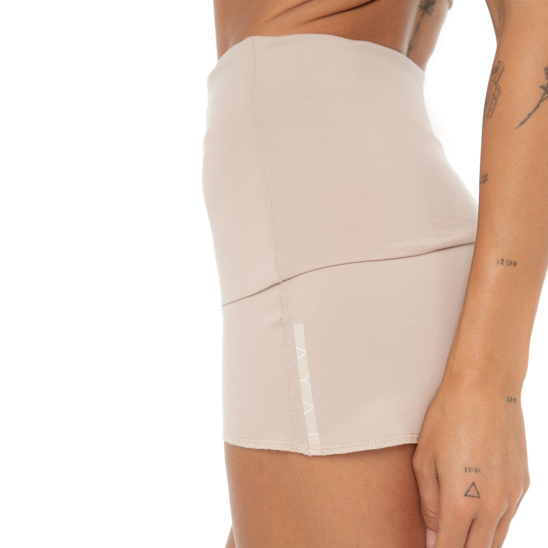 Close-up of Nove Short hem in nude with AYAI logo detail on side. **nude