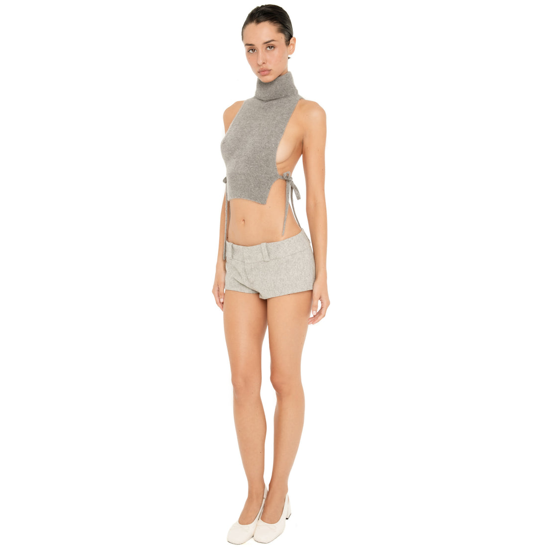 Full-length front view of model wearing the Nula Short in Dove, a low rise tailored micro short with a wide waistband and belt loops, styled with a grey knit top. **dove