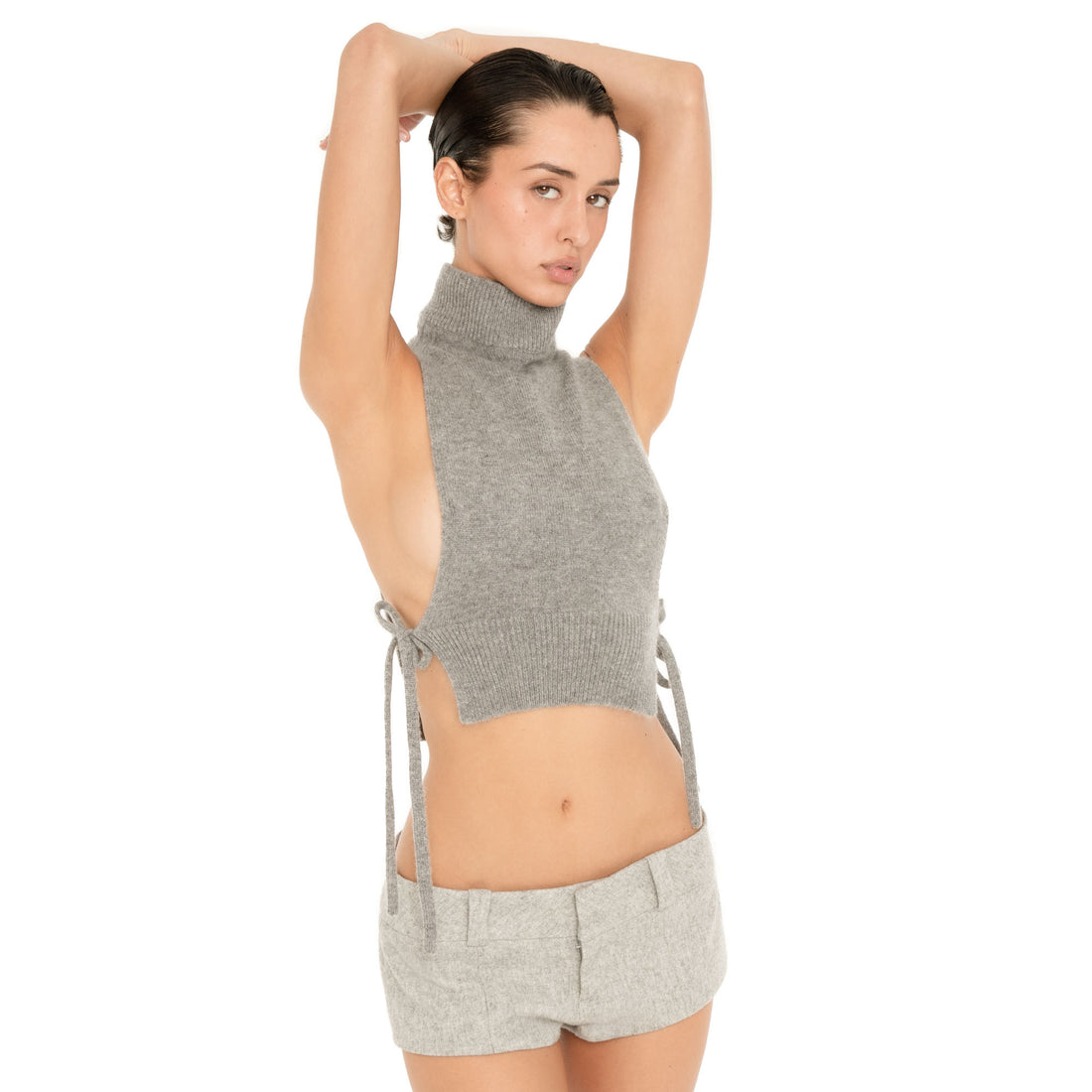 Three-quarter view of model wearing the Nula Short in Dove, showing the low rise fit and tailored micro silhouette with a grey side-tie knit top. **dove