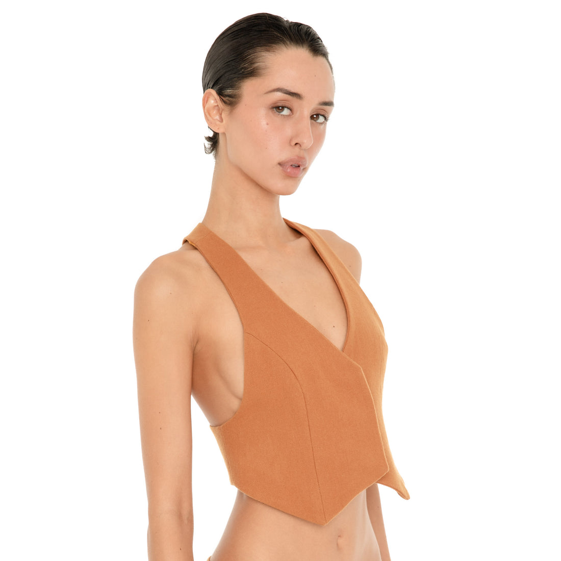 Three-quarter view of model wearing the Pau Vest in Saffron, showing the deep V neckline, fitted seaming, cropped pointed hem and low-cut armholes. **saffron