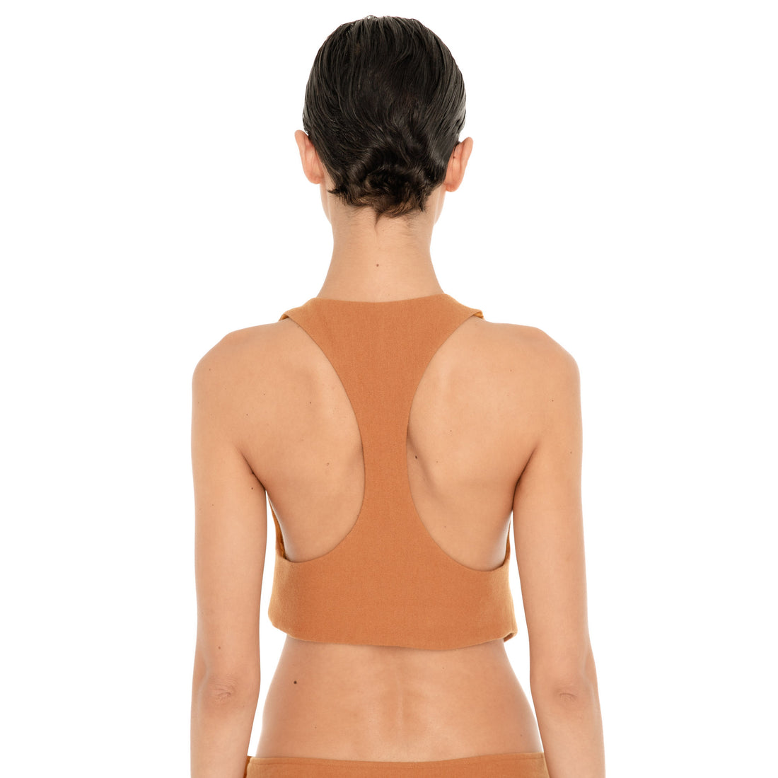 Back view of the Pau Vest in Saffron, showing the racerback-inspired shape, exposed shoulders and cropped straight back hem. **saffron