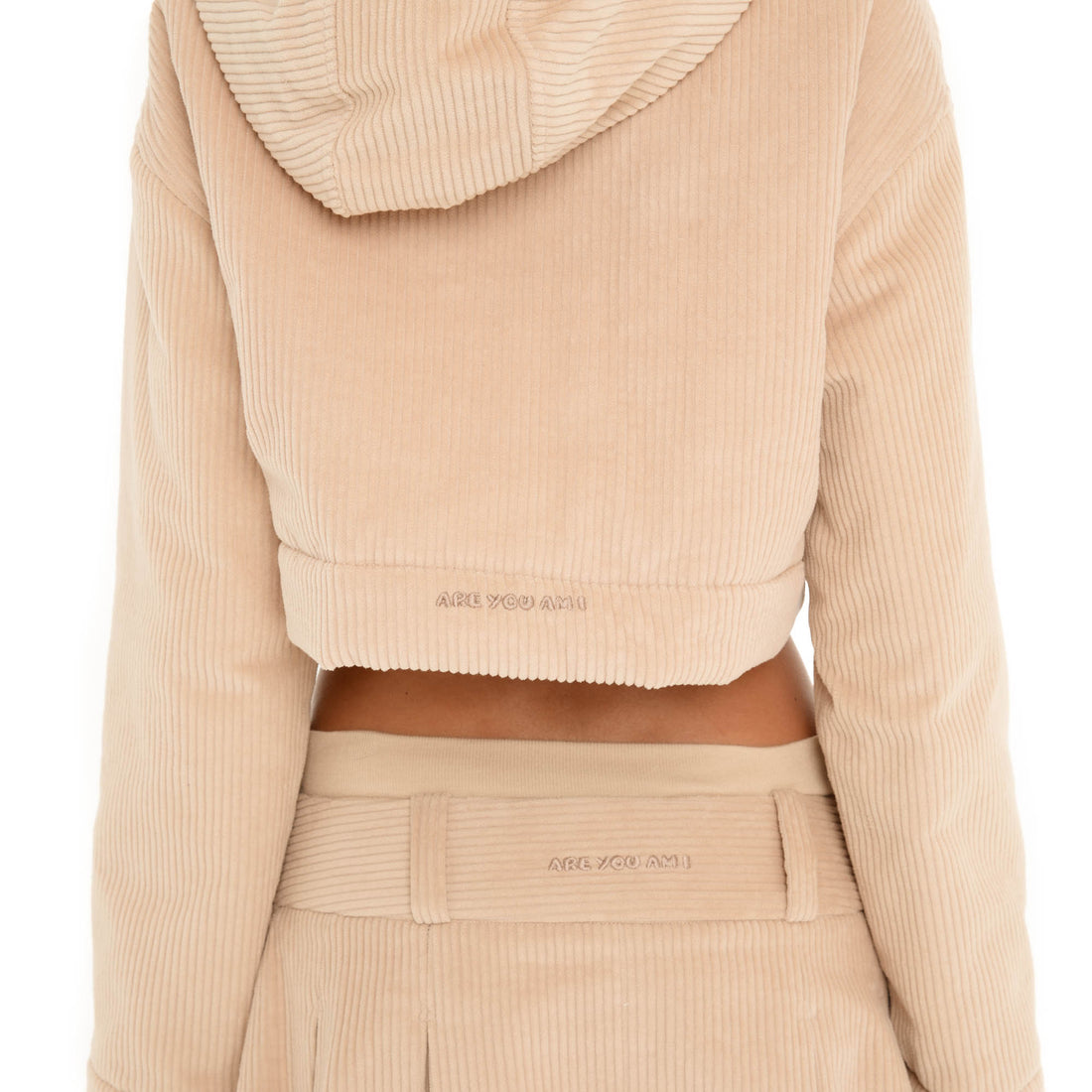 Close-up back view of the Sfera Jacket in Sand, highlighting the ribbed texture, cropped hem and embroidered Are You Am I logo. **sand