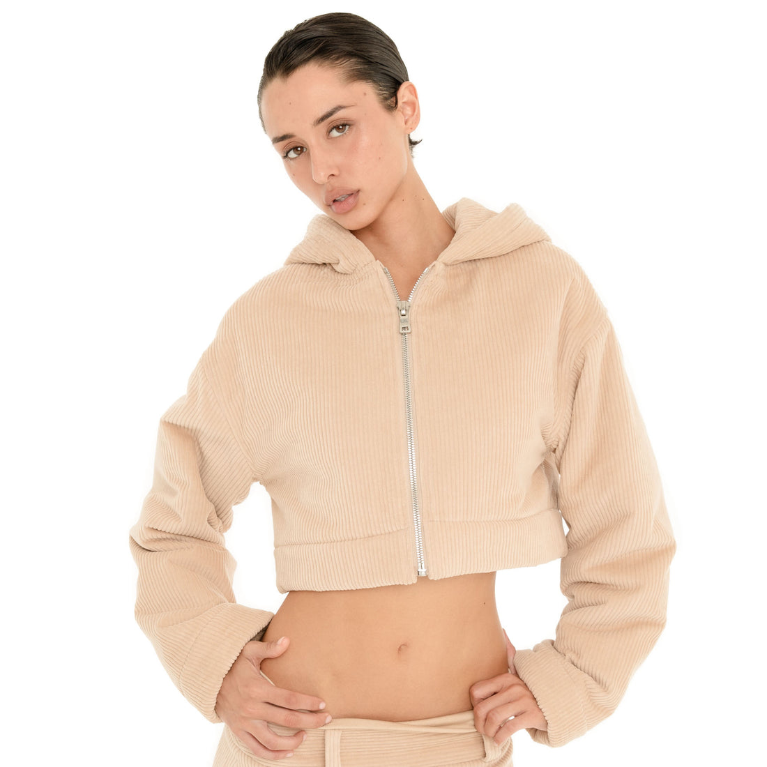 Front close-up of model wearing the Sfera Jacket in Sand, showing the silver front zipper, oversized hood, ribbed texture and cropped fit. **sand