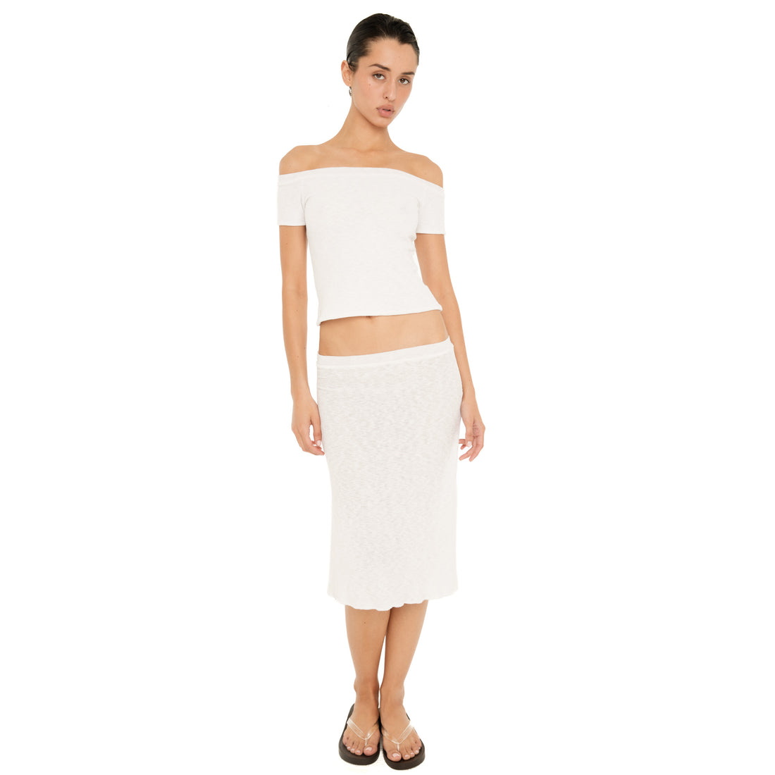 Model wearing the white Solei off-the-shoulder top with a matching white midi skirt and flip-flops **white