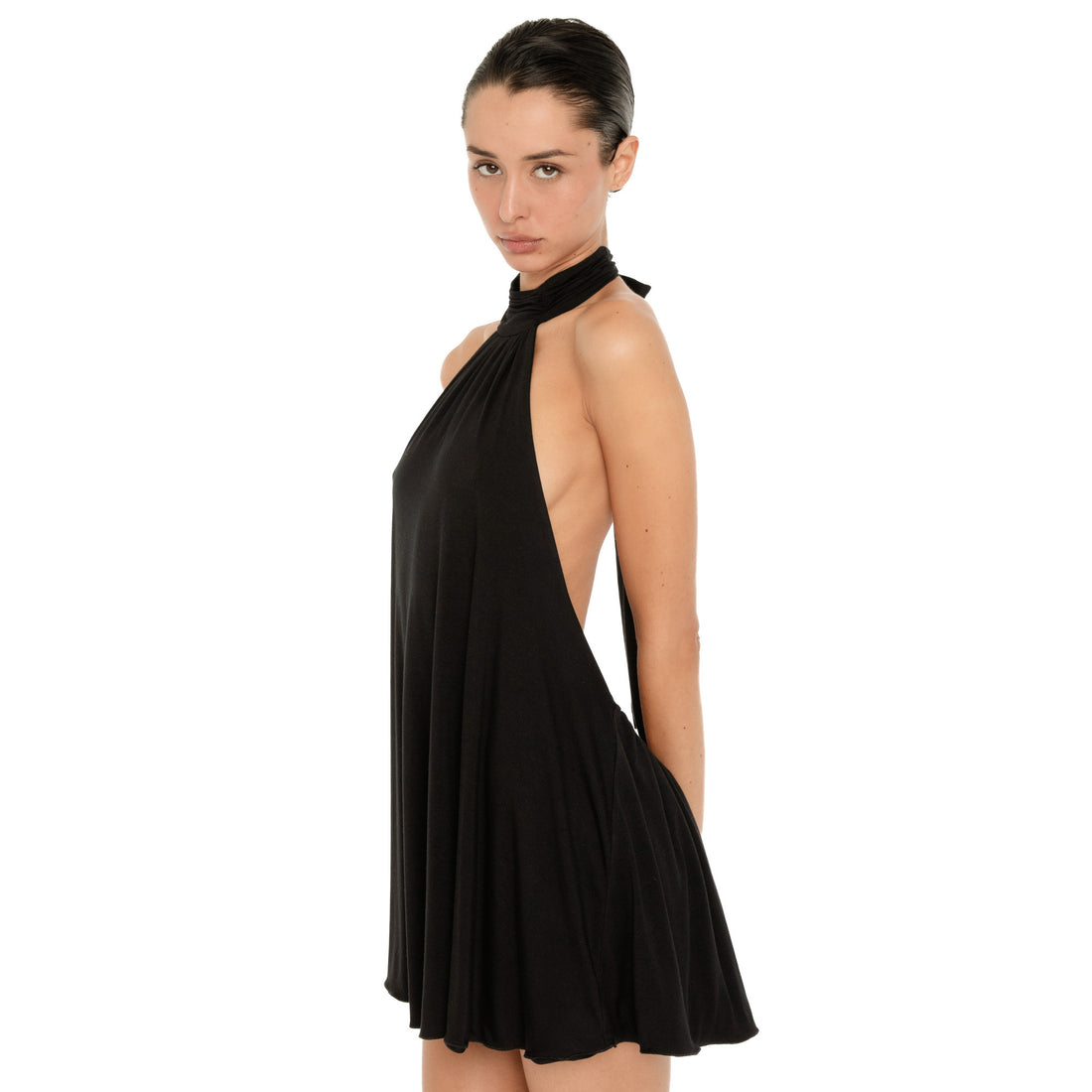 Side view of the black halter mini dress, showing the draped fabric, low cut sides, high neckline, and loose flowing shape. **black