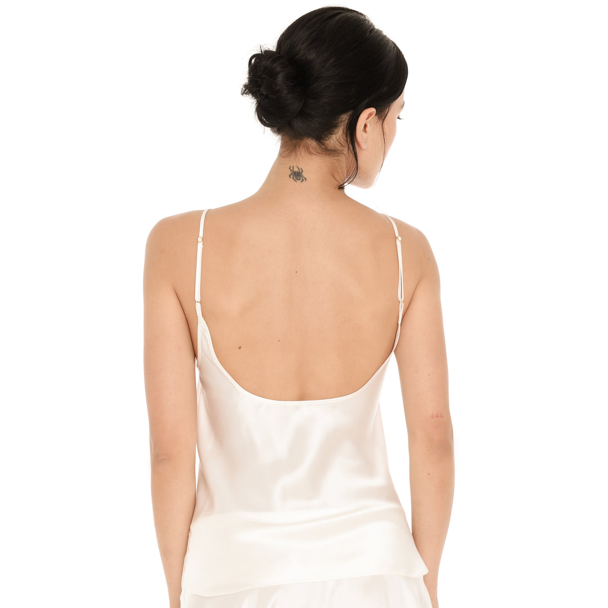 Back view of the white silk Syra Camisole, showing the low scoop back and thin adjustable straps with small gold adjusters. **white