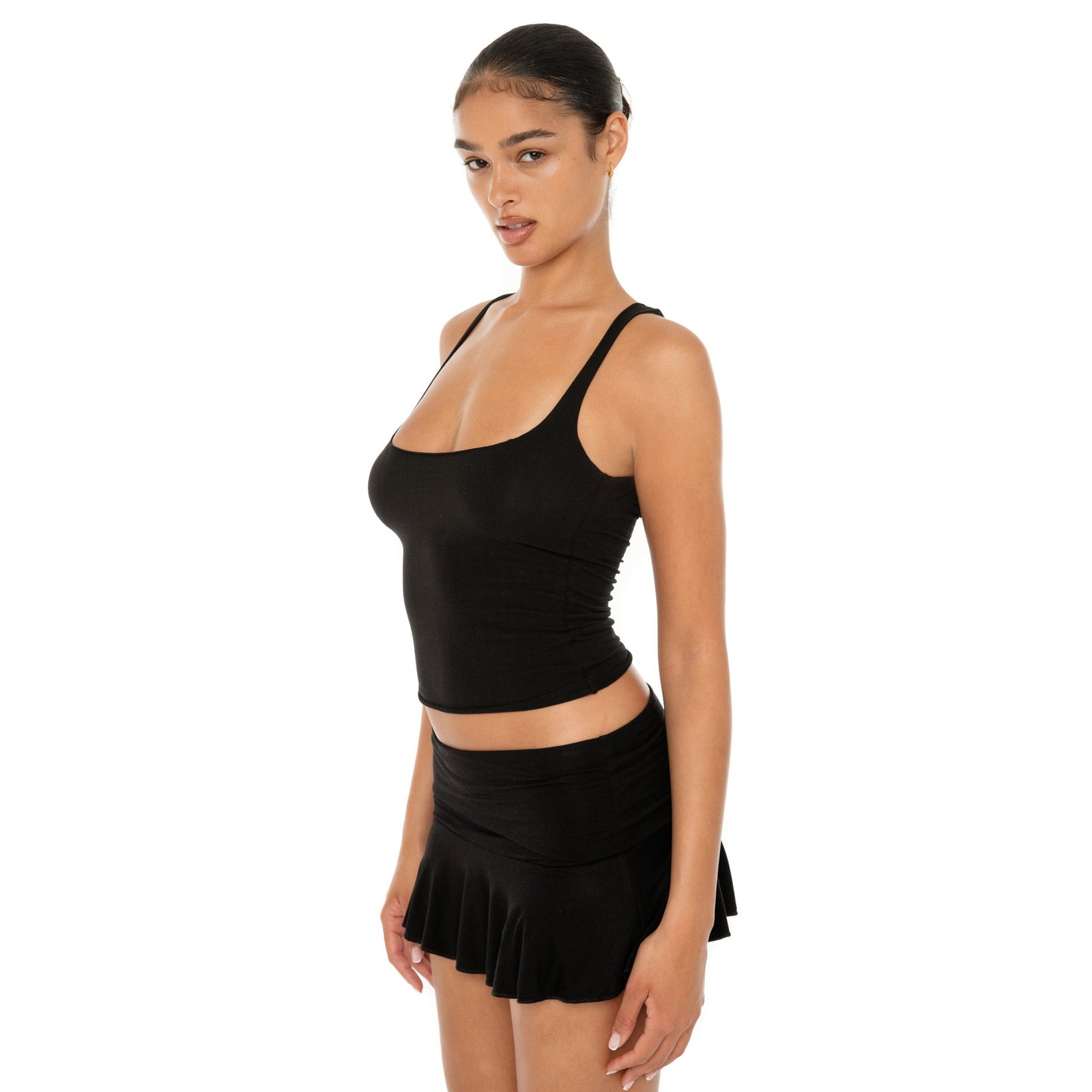 Model wearing the Naia Skirt — a low-rise mini in ultra-soft modal with spandex stretch, designed to sculpt the waist with a sleek, minimal fit.**black