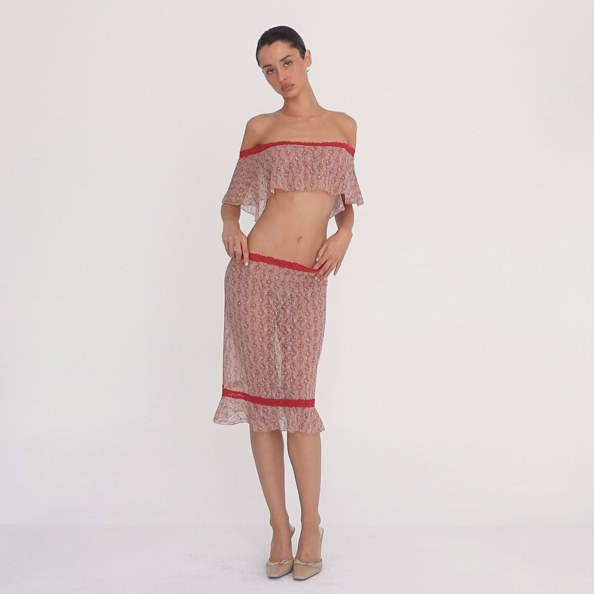 Model wearing the Cherry Blossom Liulu Skirt, moving and turning to show the low-rise fit, sheer floral lace, contrasting red lace trim, fitted silhouette, and movement of the ruffled hem **cherry blossom