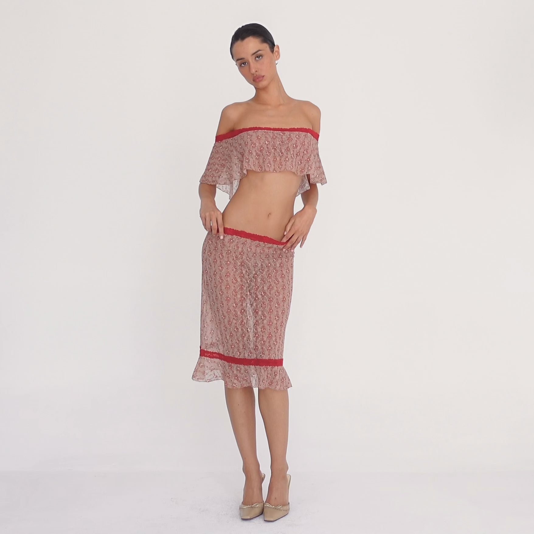 Model wearing the Cherry Blossom Liulu Skirt, moving and turning to show the low-rise fit, sheer floral lace, contrasting red lace trim, fitted silhouette, and movement of the ruffled hem **cherry blossom