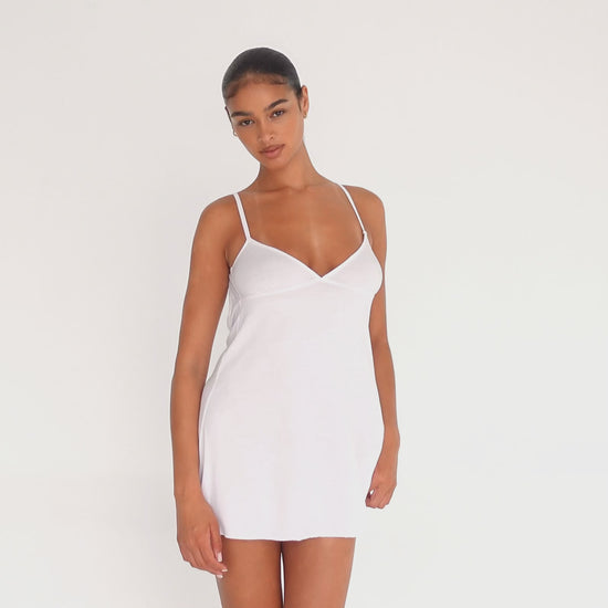 Model wearing the Ysa Dress in white — minimal bias-cut mini with delicate straps and open back, designed to skim the body with effortless movement.**white