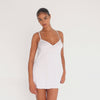 Model wearing the Ysa Dress in white — minimal bias-cut mini with delicate straps and open back, designed to skim the body with effortless movement.**white