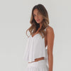 Model wearing white cropped swing cami top with adjustable straps and fluid drape, shown in motion to emphasize lightweight fabric and movement **white