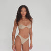 360-degree view of model wearing the Iselle Bottom in Nude, showcasing the full lingerie set from every angle including front, side, and back. The delicate lace texture, low-rise fit, and fine strap detailing are visible throughout the rotation. **nude