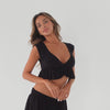 Model wearing black cropped ruffle top and matching skirt, showing front, side, and movement of stretch knit fabric and ruffle hem detail **black