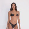 Model wearing the Iselle Bikini in black — sheer high-leg bikini in floral lace with vintage-style minimal coverage**black