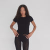 Model moving in the Are You Am I Kimi Tee in black, showcasing lightweight baby rib fit, short sleeves, and cropped hem. **black