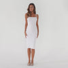 Video of model wearing a white midi dress with thin straps and a square neckline, slowly shifting between front, side, and back poses to show the fitted silhouette, smooth fabric, and mid-calf length **white