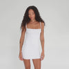 360-degree rotating view of model wearing the white Impy Illy mini dress, highlighting the body-contouring fit, spaghetti straps, and seamless silhouette from all angles. **white