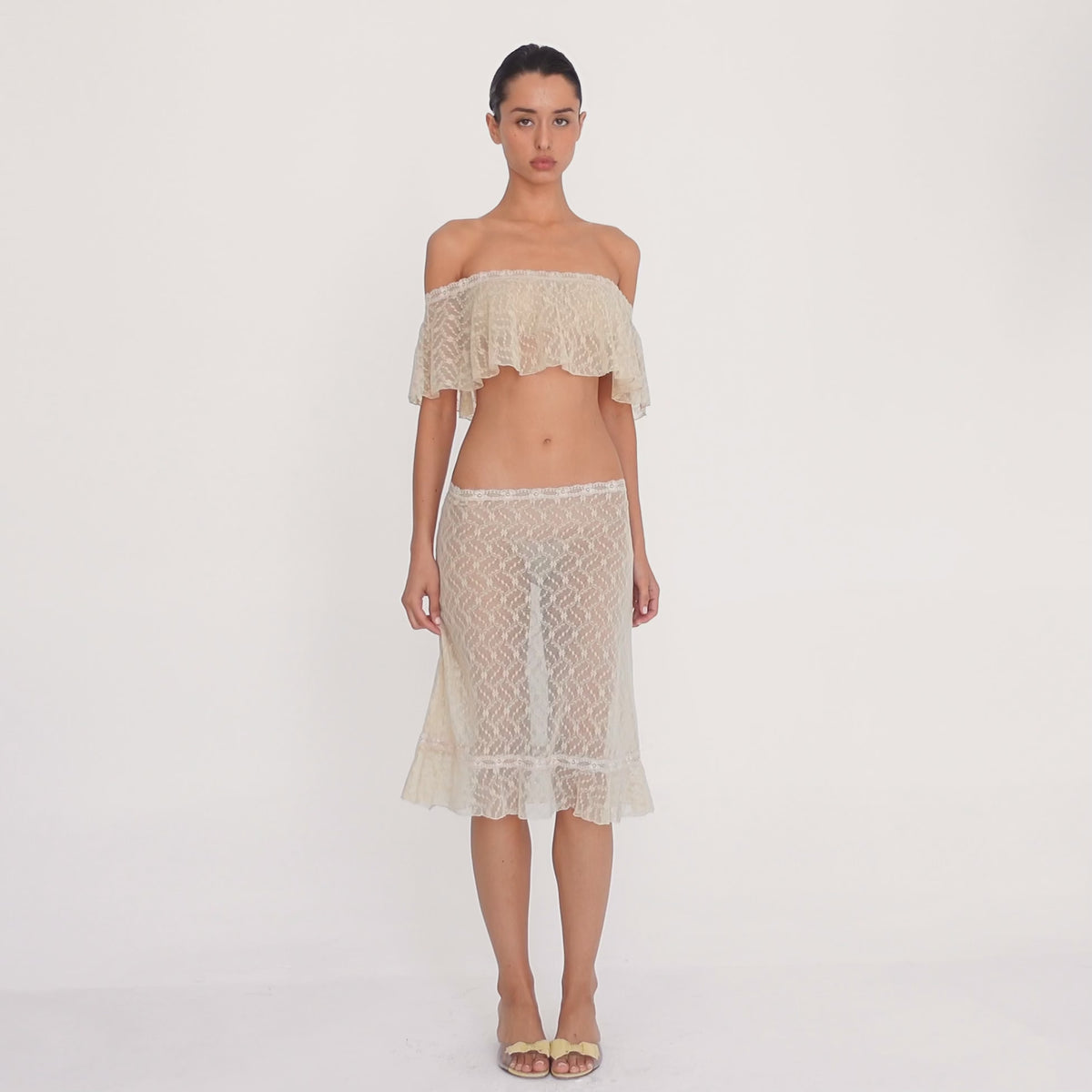 Video: Model wearing the Liulu skirt in nude, showing the sheer floral lace, low rise fit, lace trimmed waistband, midi length, and ruffled hem from multiple angles. **nude