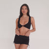 Model moving in black ribbed low-rise active shorts with adjustable side ties, showing fit, stretch, and adjustable length **black