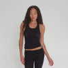 Model wearing the black Kimi Tank, showing front, side, and back views in motion to highlight the tank’s racerback cut, fitted ribbed texture, and sheer fabric. **black