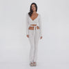 Video: Model wearing the sand Clio Pant with a matching wrap top, shown from multiple angles to highlight the low-rise fold-over waistband, fitted silhouette, ribbed fabric, side lace-up detail, and flared legs **sand